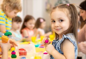 Dzieci bawią się plasteliną, co wspiera edukacja przedszkolna rozwój emocjonalny dziecka.